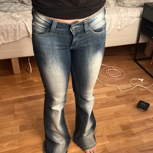 Bootcut jeans från Cheap Monday - Säljer ett par blå bootcut jeans från Cheap Monday. Jeansen har snyggt slitna detaljer och ljusare partier framtill och baktill. Modellen är låg midja och utsvängda med till. Storlek: w27 längd 30. Jeansen är lite slitna ner till annars är den i bra skick.