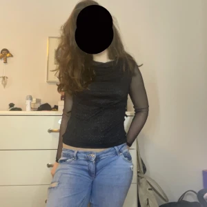 Svart glittrig mesh-top med långa ärmar - Snygg svart topp med glittrigt tyg och transparenta mesh-ärmar. Toppen har en figurnära passform och är perfekt för att sticka ut. Materialet är stretchigt och svalt, denna top är perfekt till nyår! ❤️❤️