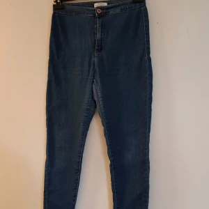 Blå skinny jeans från Bershka strl 38 - Snygga blå skinny jeans från Bershka i stretchigt denim. Modellen har hög midja, klassiska bakfickor och smal passform hela vägen ner. Perfekta till sneakers eller boots och superenkla att styla till olika looks.  Lite "tunnar" tyg mellan bena men inga hål annars fint skick
