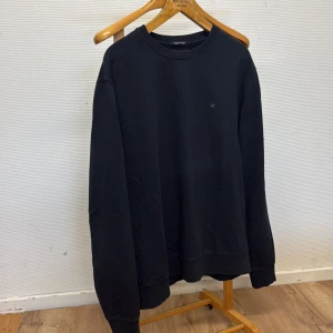 Svart sweatshirt från Junk de Luxe - En stilren svart sweatshirt från Junk de Luxe i ekologisk bomull. Tröjan har rund halsringning, diskret logga på bröstet och långa ärmar. Perfekt för dig som gillar en clean och enkel look med en touch av streetstyle.