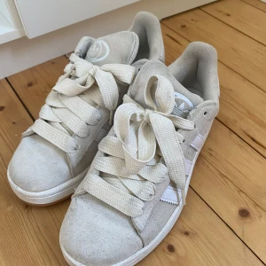 Adidas Campus sneakers i beige  - Snygga Adidas Campus sneakers i beige mocka med klassiska vita ränder och breda vita skosnören. Skorna är använda men är i väldigt bra skick! 