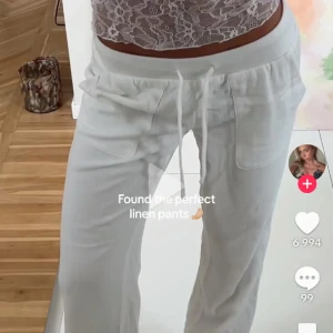 Vita lågmidjade linnebyxor - Snygga vita linnebyxor med bred resår i midjan och snörning framtill. Byxorna har raka ben och stora fickor framtill för en chill och avslappnad vibe. Perfekta för varma dagar och enkel att styla med crop tops eller skjortor.