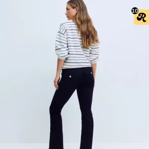 Svarta bootcut jeans från Gina Tricot - Svarta jeans med bootcut-silhuett från Gina Tricot. Klassisk femficksmodell med silverfärgade nitar och knapp, normalhög midja och stretchigt jeanstyg som sitter snyggt över höfterna och släpper ut vid bensluten.