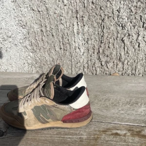 Valentino Garavani camo sneakers - Snygga Valentino Rockrunner sneakers med camouflagemönster i grönt, beige och brunt. Skorna har detaljer i mocka och skinn, röda och vita partier vid hälen samt klassisk snörning. Perfektq för alla väderförhållanden🌟 dom ör använda därav priset dom är köpte för 8000 kr och man kan få med dustbag