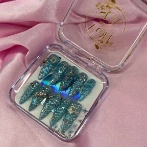 AquaStarburst (XS);Long Stiletto  - Snygga gelé långa lösnaglar med cateye glittereffekt, dekorerade med silvriga stjärnor, pärlor och 3D-detaljer. Naglarna har spetsig form och coolt handmålade mönster med 3D nailart, som ger en unik look. Perfekt för dig som vill sticka ut och älskar detaljerade naglar. I storlek XS: 14 mm, 11 mm, 11,5 mm, 10 mm, 8 mm 