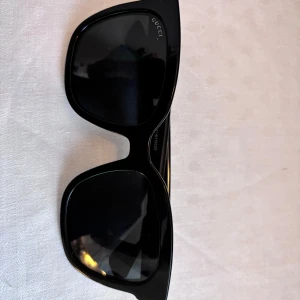 Svarta solglasögon från Gucci - Säljer mina Gucci solglasögon i modell: GG0034SN färg:001, storlek: 54-20. Aldrig använda, köpa på Synsam för 3300kr. Grå/svarta glas. 