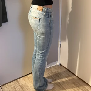 Ljusblå bootcut jeans från Replay - Säljer ett par ljusblå jeans från Repe med bootcut passform. Jeansen har klassisk femficksdesign, låg midja och subtila slitningar på bakfickorna. Tillverkade i mjukt denim med snygg tvätt och dragkedjegylf.