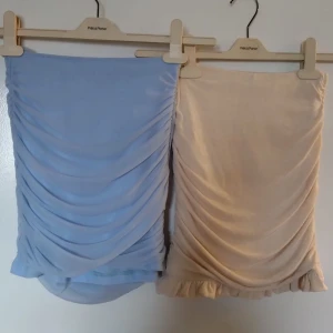 Två kjolar i blått och beige - Jag säljer två snygga kjolar i blått och beige. Båda har en draperad design med volangdetaljer längst ner🤩