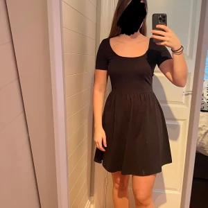 Svart kortklänning med kortärmad design - Snygg svart kortklänning med korta ärmar och en rundad halsringning. Klänningen har en dragkedja i ryggen.