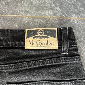 Svarta jeans från McGordon - Snygga svarta jeans från McGordon i storlek 31-30. Tillverkade av 99% bomull och 1% elastan för en bekväm passform. Klassisk design med fem fickor och knappgylf. Perfekta för en stilren look.