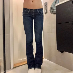 Blå jeans med bootcut - Snygga blå jeans med bootcut-stil och låg midja. Perfekta för en avslappnad look. Klassisk femficksdesign och knappgylf.
