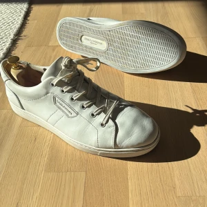 Vita sneakers från Dolce & Gabbana - Snygga vita sneakers från Dolce & Gabbana med klassisk snörning och stilren design. Perfekta för en avslappnad men ändå elegant look. Tillverkade i skinn för en lyxig känsla.