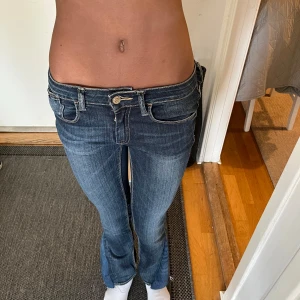 Lågmidjade jeans - Lågmidjade Snygga blå jeans från Le Temps des Cerises med klassisk femficksdesign och knappgylf. Jeansen har en smal passform och är perfekta för en stilren look. De är tillverkade i ett slitstarkt denimtyg som ger en bekväm känsla hela dagen. Stl Xs, tyvärr är de för små på mig så kan tyvärr inte fixa bilder med de på. Sytt ut de själv! Midjemått: 35 cm. Innerbenslängd: 77 cm.