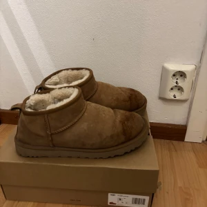 Bruna ultra mini UGGs - Säljer ett par bruna UGG boots med tjockt mjukt foder inuti. De är perfekta för kalla dagar. Man kan se att de är använda framme vid tån men det går också att få bort om man verkligen vill få bort det (se bild). Annars är de i bra kvalitet!