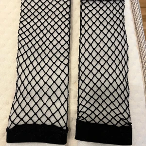 Svarta nätstrumpor - Snygga svarta nätstrumpor med elastiska kanter. Perfekta för att ge en edgy touch till din outfit. De har ett klassiskt fisknätsmönster som är både trendigt och stilrent.
