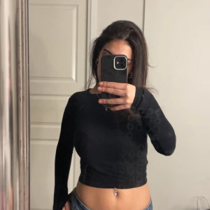 Svart croppad topp - Säljer en svart croppad topp med lång ärm. Perfekt för en stilren look. Toppen har en tight passform och är tillverkad i ett mjukt material.