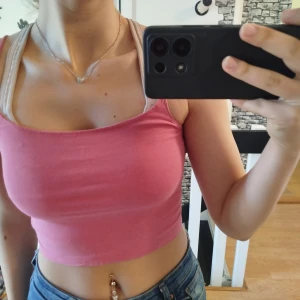 Rosa croppad tubtopp - Säljer en söt rosa croppad tubtopp perfekt för sommardagar. Toppen är ärmlös och har en enkel design som gör den lätt att matcha med olika outfits.