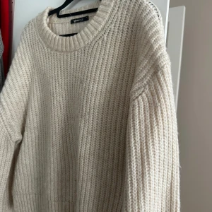 Beige stickad tröja från Gina Tricot - Mysig beige stickad tröja från Gina Tricot med rund halsringning. Perfekt för kyliga dagar med sin mjuka och bekväma passform. Tröjan har långa ärmar och ribbade detaljer vid ärmslut och nederkant.
