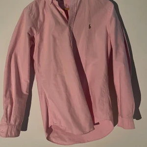 Rosa skjorta från Ralph Lauren - Snygg rosa skjorta från ralph lauren, perfekt till sommarn. Väldigt stor i storleken nästan en L. Billig och snabbt köp uppskattas 