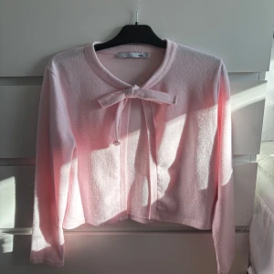 Rosa kofta med rosett - Säljer en söt rosa kofta med en dekorativ rosett framtill. Koftan har långa ärmar och är tillverkad i ett mjukt material. Perfekt för en stilren och feminin look. Hör av dig vid intresse! 💖