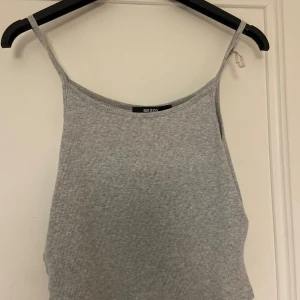 Grå ribbad linnetopp från Bik Bok - Säljer en stilren grå ribbad linnetopp från Bik Bok. Perfekt för varma dagar med sin enkla design och smala axelband. Toppen är i storlek M och passar utmärkt till både jeans och kjol.
