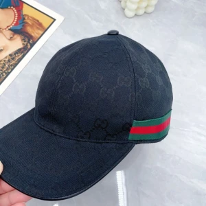 Gucci keps - Snygg svart keps med diskret mönster och en randig detalj i grönt och rött på sidan. Perfekt för att ge din outfit en lyxig touch. Justerbar passform för extra komfort. Parfeckt till våren/sommaren skov för funderingar 😉pris kan diskutera vis snabbt köp