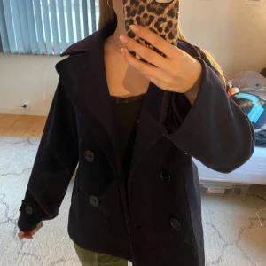 Mörkblå design by si kappa - Snygg mörkblå kappa med dubbelknäppning och breda slag. Jackan har en klassisk design med knappar på ärmsluten och en rak passform. Perfekt för en stilren look. Säljer denna pågrund av att den inte kommer till användning. ❤️