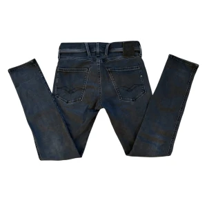 Svarta Replay Jeans - Snygga svarta jeans från Replay i modellen ANBASS. De har en klassisk femficksdesign med knapp och dragkedja framtill. Jeansen har en stilren look med diskreta sömmar och en bekväm passform. Dem är i också i Hyperflex vilket gör dem extremt bekväma‼️Kom med frågor😇