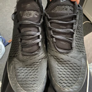 Svarta Nike Air Max 270 sneakers - Säljer ett par svarta Nike Air Max 270 sneakers. Skorna har en luftig mesh-ovandel och den ikoniska Air Max-dämpningen i hälen. Perfekta för både stil och komfort. Snörning framtill för en säker passform.