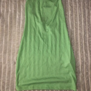 Grön ribbad klänning - Snygg grön ribbad klänning med smala axelband. Perfekt för en somrig look. Klänningen har en enkel och stilren design som gör den lätt att matcha med olika accessoarer Aldrig använt .