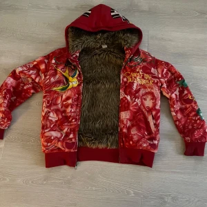 Röd Ed Hardy zip up med tryck - Säljer en cool röd zip up från Ed Hardy med tryck och broderi. Tröjan har en luva och dragkedja framtill samt fuskpäls på insidan. Saknar storlek men passar rätt bra på mig som är 180 lång.