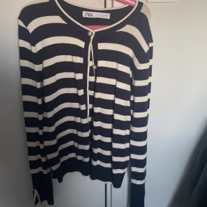 Randig kofta från Zara - Snygg randig kofta från Zara i svart och vit. Den har långa ärmar och knappar framtill. Perfekt för en stilren look.
