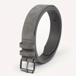 Grått mockabälte - Snyggt grått bälte i mocka med en stilren metallspänne. Perfekt för att ge en elegant touch till din outfit. Bältet har flera hål för justerbar passform.