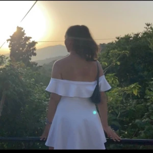 Studentklänning - Säljer en stilren vit offshoulder klänning från Guess. Klänningen har en kort längd och är perfekt för varma dagar. Den har en elegant volangdetalj runt axlarna som ger en romantisk touch. Klänningen är dessutom perfekt för studenten! Klänningen är endast använd en gång och har därför inga defekter 