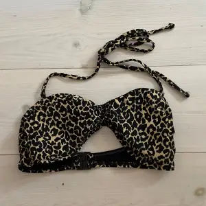 Trendig bikiniöverdel med leopardmönster och knytband i nacken. Den har en praktisk spänne baktill för enkel justering. Perfekt för en dag på stranden eller vid poolen.