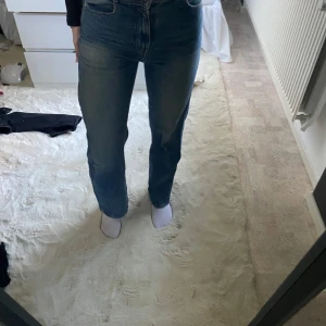 Blå jeansbyxor - Snygga blå jeansbyxor med hög midja och straight passform. Perfekta för en avslappnad stil. Klassisk design med fem fickor och knappgylf.