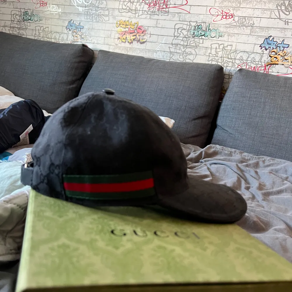 Snygg svart keps från Gucci med det ikoniska GG-mönstret. Kepsen har en grön och röd randdetalj på sidan och justerbar rem baktill. Perfekt för att ge en lyxig touch till din outfit. Kepsen är äkta och köpt för 5650. Pris går att diskutera vid snabb affär . Asusteet.