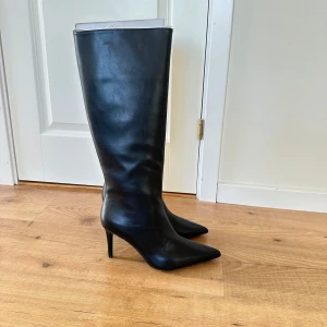 Svarta stövlar med spetsig tå - Snygga svarta stövlar  med spetsig tå och klack. De har en dragkedja på sidan för enkel på- och avtagning. Perfekta för en stilren outfit. Som bild visar så går klackarna till precis under knät. Säljer dom eftersom jag aldrig fått användning av dom.