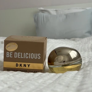 Be Delicious parfym från DKNY - Säljer en fräsch och fruktig parfym från DKNY, Be Delicious. Flaskan har en unik äppelformad design i glas och metall med en gyllene ton. Perfekt för den som älskar en doft av friska äpplen och blommor. Kommer i originalförpackning.