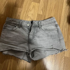 Grå jeansshorts med fransar - Snygga grå jeansshorts med fransiga kanter och klassisk femficksdesign. Perfekta för en avslappnad stil. De har en knapp- och dragkedjestängning framtill. 