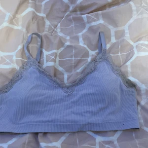 Ljuslila ribbad linnetopp med spetsdetaljer - Säljer en söt ljuslila ribbad linnetopp med justerbara axelband och spetsdetaljer längs kanterna. Perfekt för en avslappnad look eller som ett lager under andra plagg.