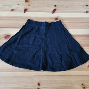 Svart kortkjol - Snygg svart kortkjol i ett enkelt och stilrent snitt. Perfekt för att matcha med olika toppar och accessoarer. Kjolen har en elastisk midja för extra komfort.