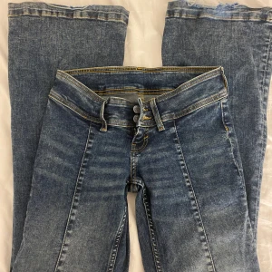 low bootcut jeans - Säljer ett par blå jeans med sömmar längs benen. Storlek: W25/L32 använda cirka två gånger!