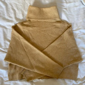 Beige/gul polotröja från Gina Tricot - Säljer en mysig beige polotröja från Gina Tricot. Tröjan har en hög krage och något croppad.