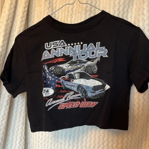 Svart croppad t-shirt med biltryck🖤 - Cool svart croppad t-shirt från Divided med ett häftigt biltryck och texten 'USA Annual Tour' på framsidan. 🛞