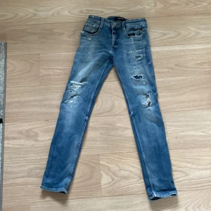 Blå jeans från Replay - Säljer ett par snygga blå jeans från Replay i modellen Anbass. De har en slim passform och är tillverkade i hållbar bomull. Jeansen har slitna detaljer och en klassisk femficksdesign. Perfekta för en avslappnad stil.
