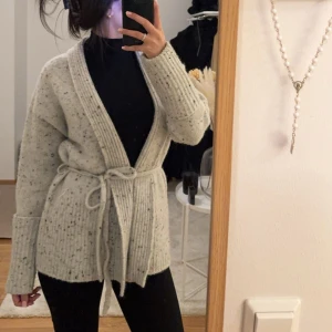 Beige stickad kofta med knytband - Mysig beige stickad kofta med knytband i midjan. Använd 2-3 gånger, skicket är som nytt. Inga defekter. Säljer då jag har tillräckligt med koftor. 🤍🩶🩶🩶köpt för 599kr 