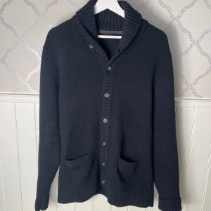 Svart kofta från BAR - Snygg svart kofta från BAR med ribbad krage och knappar framtill. Den har två praktiska fickor där framme. Schysst tröja till lite kyligare sommardagar! Kom med prisförslag!!