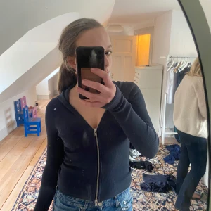 Mörkblå ribbad hoodie med dragkedja - Säljer en mörkblå ribbad hoodie med dragkedja framtill. Tröjan har långa ärmar och en åtsittande passform.