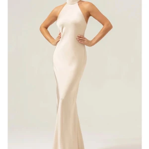 Champagnefärgad Balklänning - Säljer denna superfina champagnefärgade klänning med halterneck och öppen rygg. Klänningen är i helt nytt skick och har aldrig använts, säljer den pga att den inte passade mig och gick inte att skicka tillbaka. Skriv om ni vill ha bild på eller några andra funderingar!💕Orgenalpris - 850